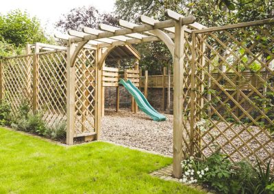 latticed fence leading to children's wooden play platform with swing